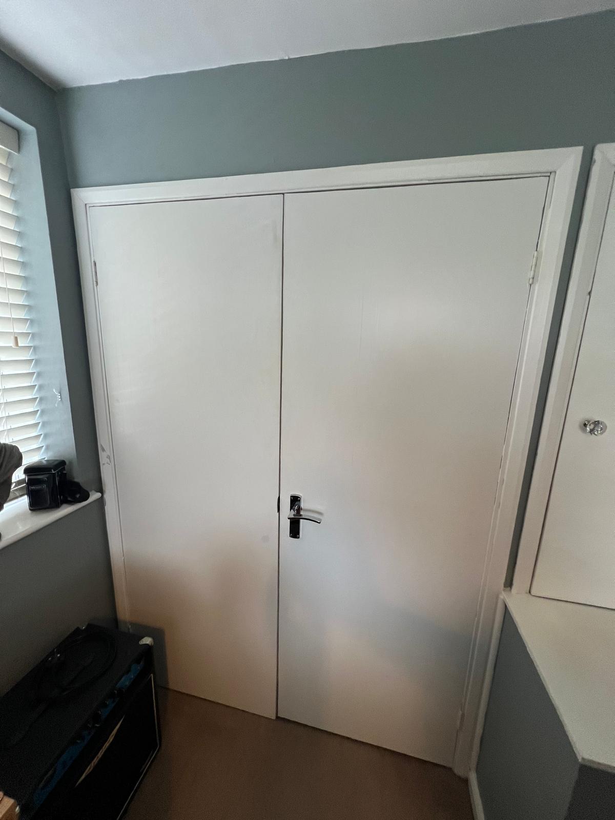 Fitted alcove wardrobe with white doors before removal