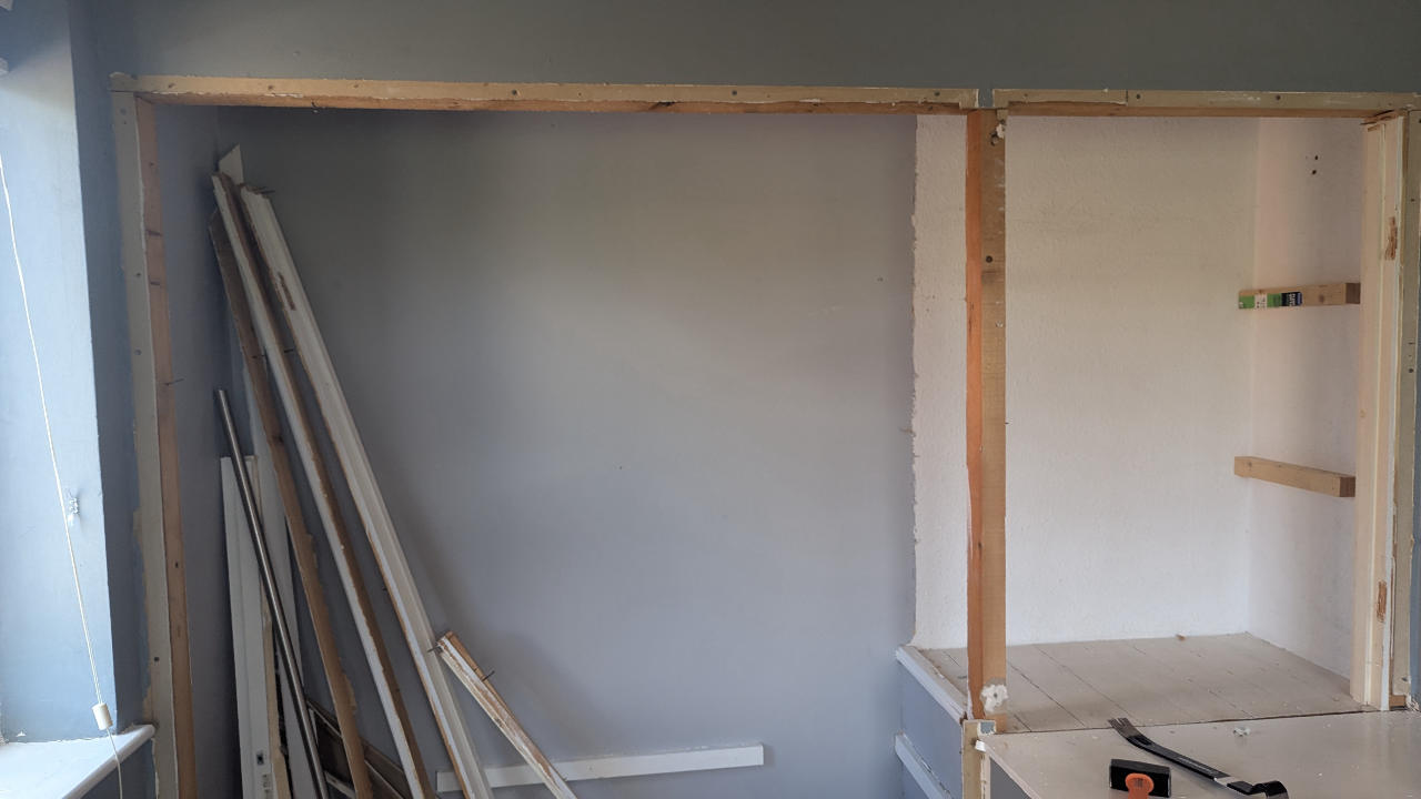 Fitted alcove units being dismantled in place, old panels stacked tidily
