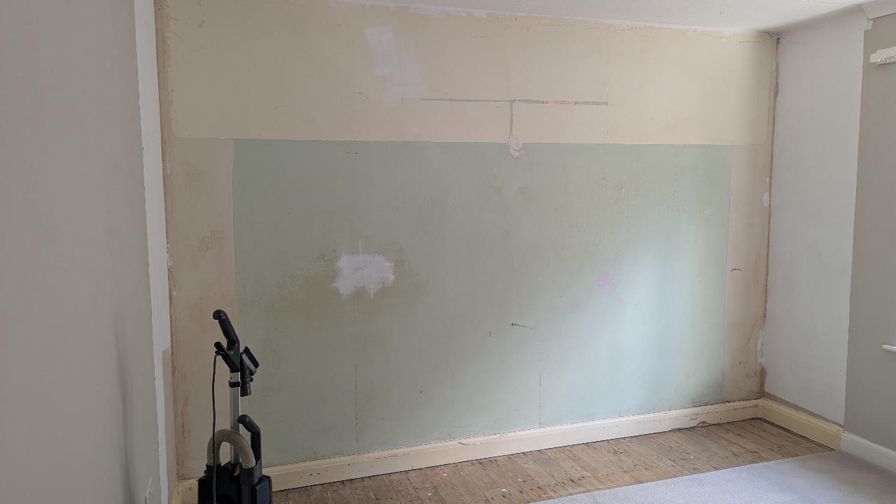 Bedroom wall cleared to bare plaster and floorboards after fitted wardrobes were removed